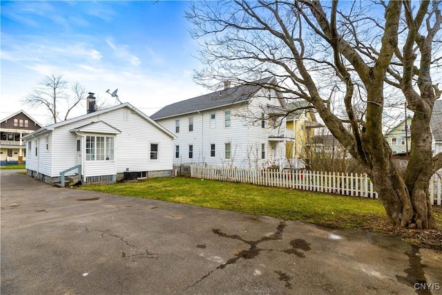 rear view of property with central AC, fence, a yard, and a chimney