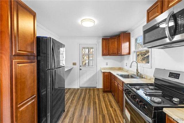 kitchen featuring crown molding, dark wood-style flooring, light countertops, a sink, and stainless steel appliances