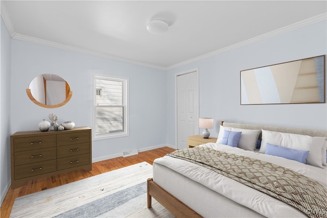 bedroom with visible vents, baseboards, ornamental molding, and wood finished floors