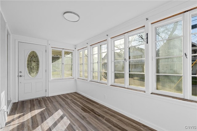 unfurnished sunroom with baseboards and wood finished floors