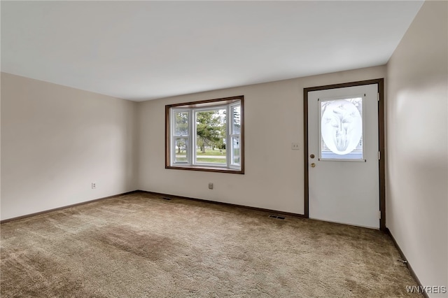 foyer entrance with visible vents, baseboards, and carpet flooring