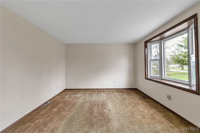 spare room featuring visible vents, baseboards, and light carpet