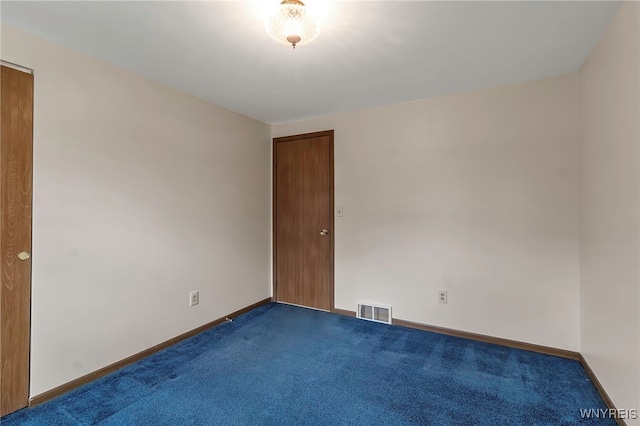 spare room with dark carpet, visible vents, and baseboards