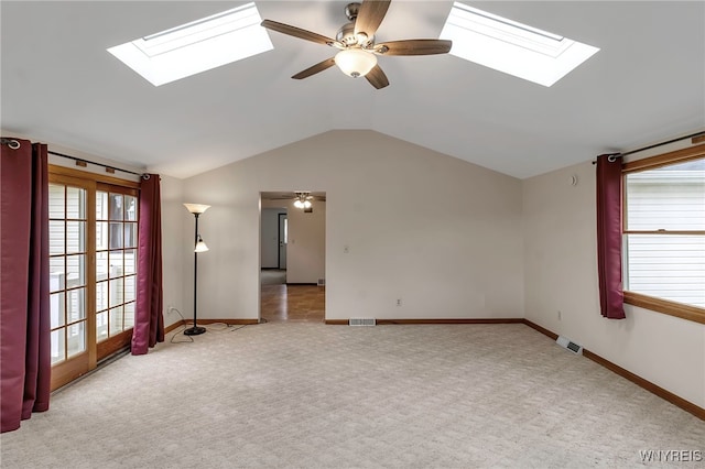 carpeted spare room with baseboards, a ceiling fan, visible vents, and lofted ceiling with skylight