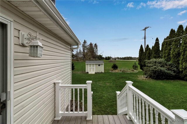 wooden deck featuring a yard, a shed, and an outbuilding