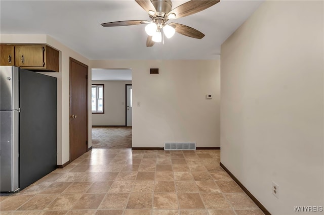 interior space featuring visible vents, baseboards, freestanding refrigerator, and a ceiling fan