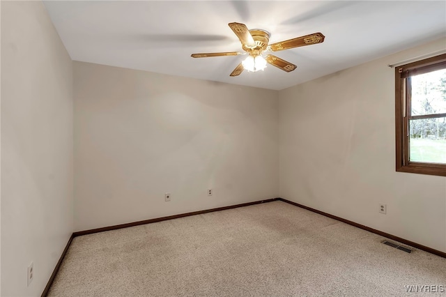 spare room with light colored carpet, visible vents, baseboards, and a ceiling fan