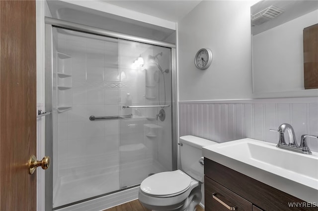 bathroom with vanity, toilet, a shower stall, wainscoting, and visible vents