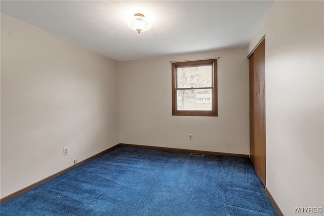 carpeted empty room featuring baseboards