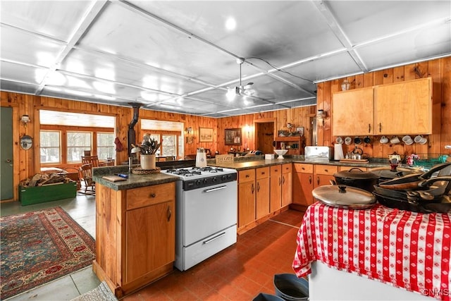 172 Green St, Ephratah, NY 13452 - kitchen featuring dark countertops, wooden walls, brown cabinets, and gas range gas stove