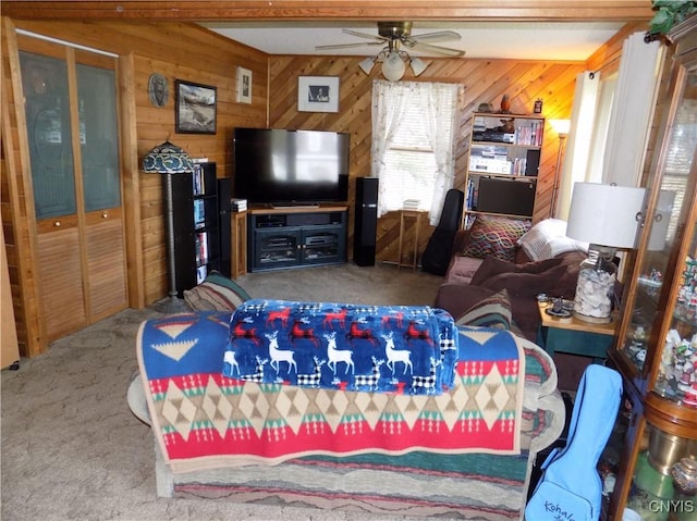 carpeted living room with a ceiling fan and wood walls
