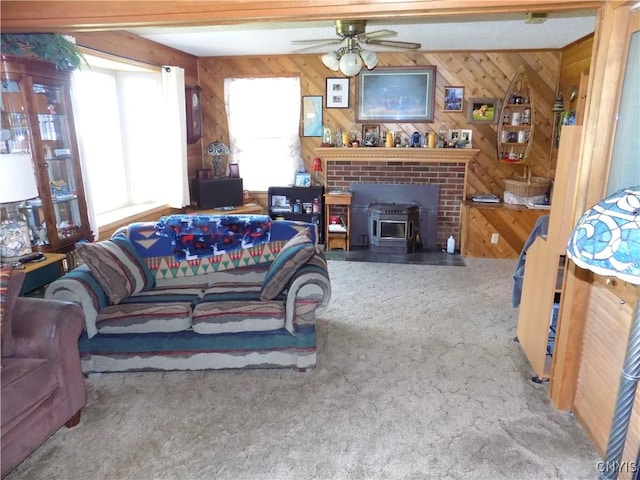 carpeted living room featuring a wood stove, ceiling fan, and wood walls