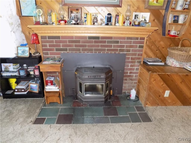room details featuring a wood stove, carpet flooring, and wood walls