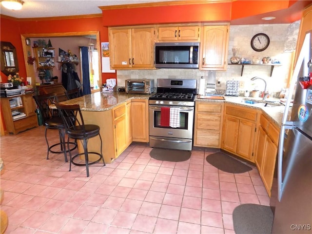 kitchen with a sink, light tile patterned floors, crown molding, a peninsula, and appliances with stainless steel finishes