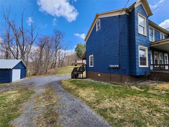 view of side of home with an outbuilding, a detached garage, and gravel driveway