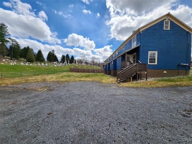 view of side of home featuring fence and stairway