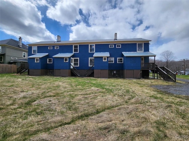 rear view of property with a yard and stairway