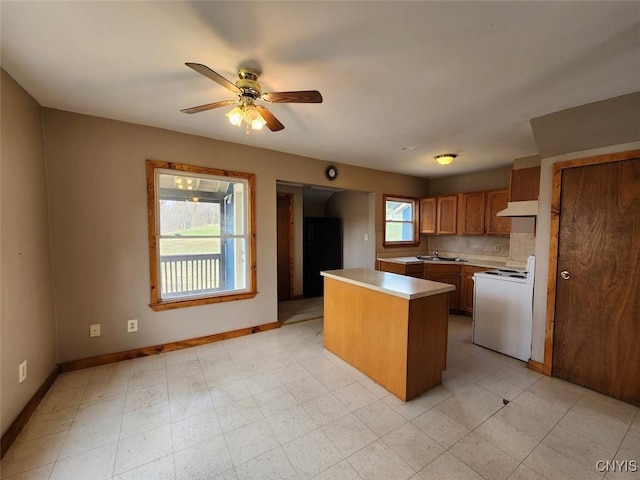 kitchen with light countertops, a ceiling fan, under cabinet range hood, white electric range, and brown cabinetry