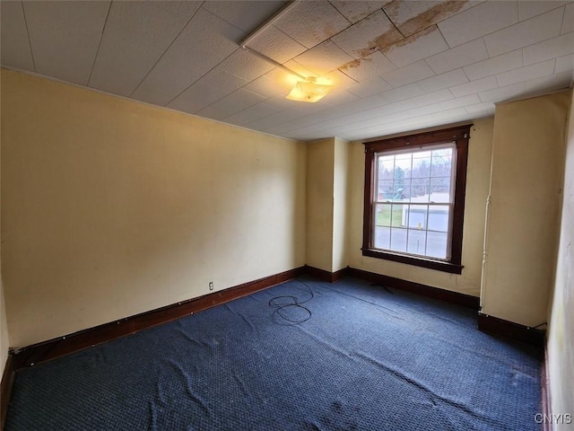 unfurnished room with dark colored carpet and baseboards
