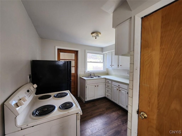 kitchen featuring freestanding refrigerator, white range with electric cooktop, a sink, light countertops, and dark wood-style floors