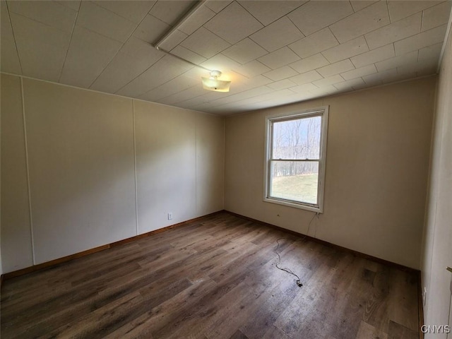 spare room with baseboards and wood finished floors