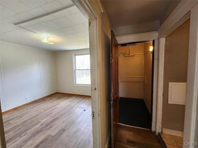 corridor featuring baseboards and wood finished floors