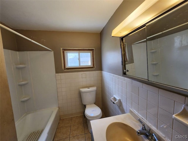 bathroom with a wainscoted wall, toilet, shower / bath combination, tile walls, and tile patterned floors