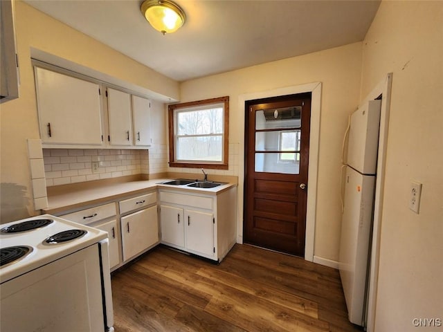 kitchen with tasteful backsplash, white cabinets, a sink, white appliances, and dark wood-style floors