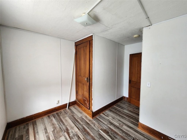 unfurnished room with baseboards, a textured ceiling, and wood finished floors