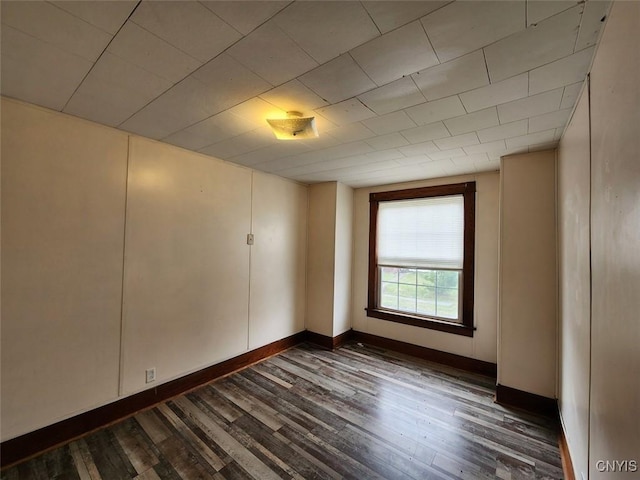 empty room featuring dark wood-type flooring and baseboards