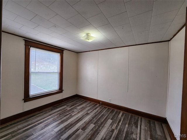 unfurnished room with dark wood-type flooring, baseboards, and crown molding