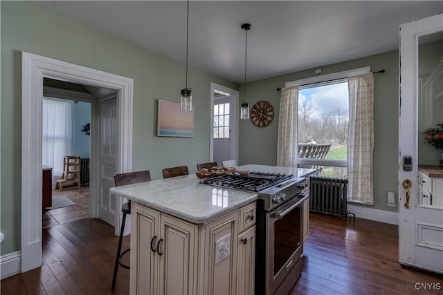 11853 State Route 12e, Lyme, NY 13622 - kitchen with dark wood-style flooring, cream cabinets, a kitchen bar, radiator, and stainless steel range with gas stovetop