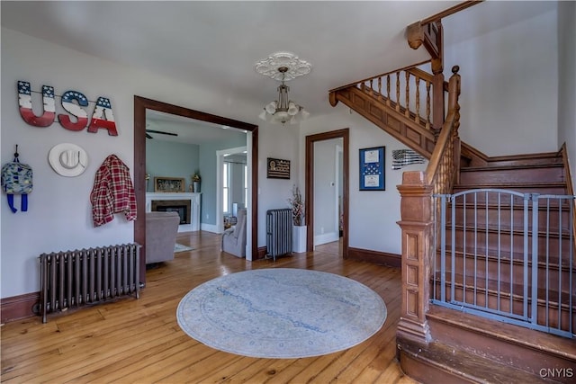 11853 State Route 12e, Lyme, NY 13622 - foyer featuring radiator, an inviting chandelier, a glass covered fireplace, stairs, and wood-type flooring