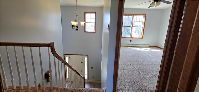 staircase featuring carpet floors, baseboards, a baseboard heating unit, and ceiling fan with notable chandelier