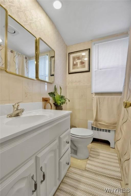 4757 N Bailey Ave, Amherst, NY 14226 - bathroom with vanity, tile patterned flooring, toilet, tile walls, and a baseboard radiator