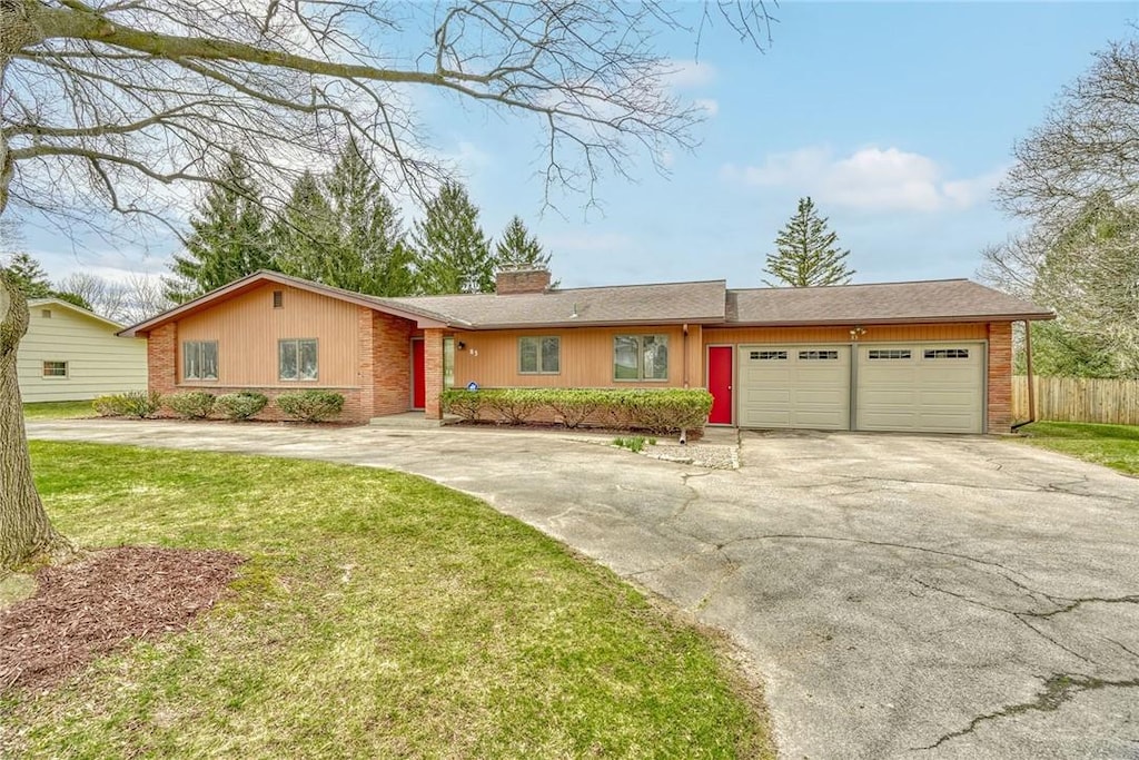 ranch-style home featuring a chimney, driveway, an attached garage, a front yard, and fence