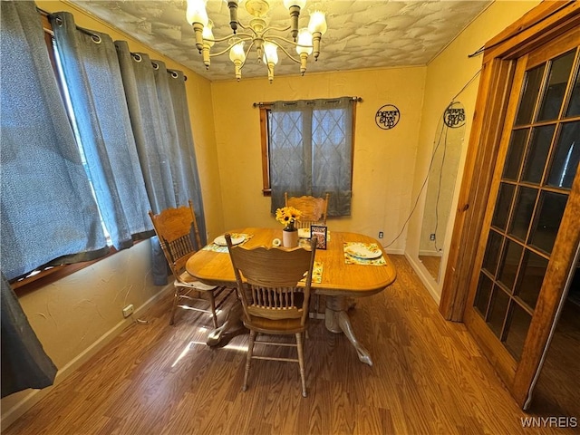 dining space with wood finished floors, an inviting chandelier, and baseboards