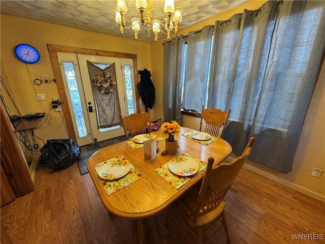 dining area with baseboards, an inviting chandelier, and wood finished floors