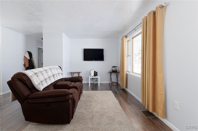 living room with dark wood-style floors, baseboards, visible vents, and a textured ceiling