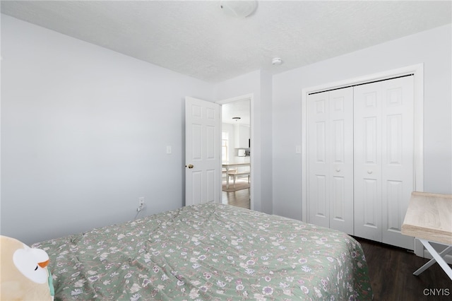 bedroom featuring a textured ceiling, wood finished floors, and a closet
