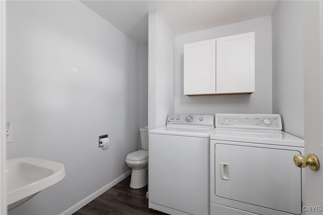 laundry area featuring baseboards, a sink, laundry area, dark wood-style floors, and washing machine and clothes dryer