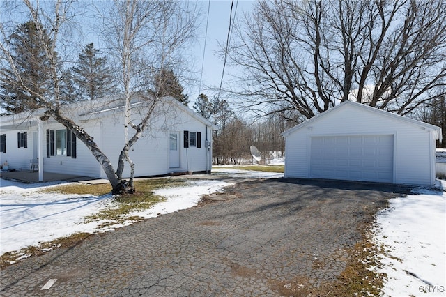 view of snow covered exterior featuring a garage and an outbuilding
