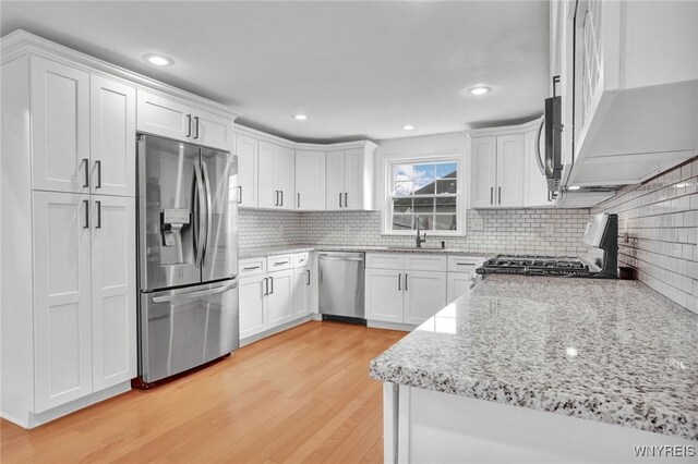 kitchen featuring light wood-style floors, appliances with stainless steel finishes, a sink, and white cabinets