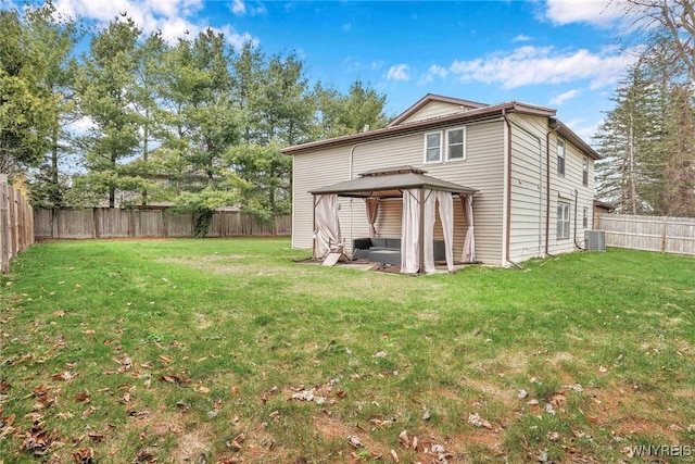 rear view of property with a gazebo, a fenced backyard, a yard, and central AC