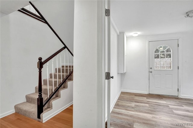 entryway featuring wood finished floors, baseboards, and stairs