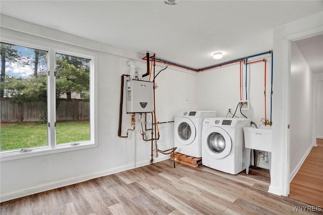 washroom with water heater, baseboards, independent washer and dryer, laundry area, and wood finished floors