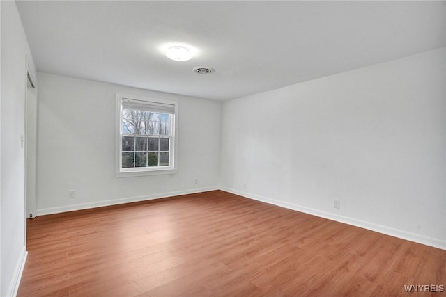 spare room featuring visible vents, baseboards, and wood finished floors