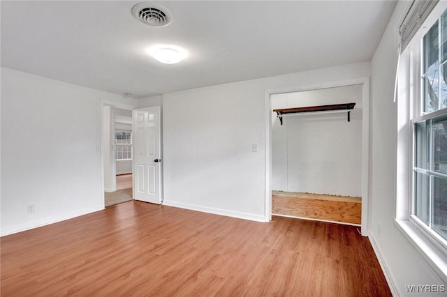 unfurnished bedroom featuring visible vents, baseboards, a closet, and wood finished floors