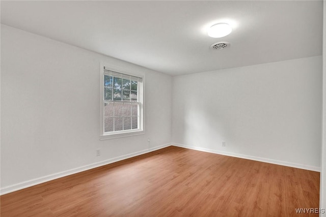 spare room with visible vents, baseboards, and wood finished floors
