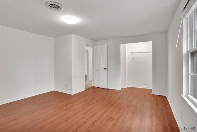 unfurnished bedroom featuring visible vents, baseboards, multiple windows, and wood finished floors